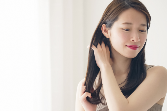 手櫛で髪を整えるストレートヘアの女性